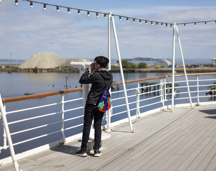On the Verandah Deck, a visitor looking through a telescope.