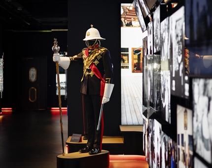 A look at Britannia's new Visitor Centre. There is a cascading wall of images on the right hand side, and a mannequin in a Royal Marine's band uniform.