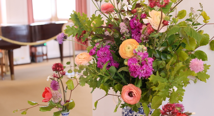 A display of flowers including ranunculus, stocks and oak leaves.